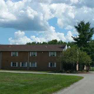 A peaceful residential building surrounded by greenery under a blue sky.