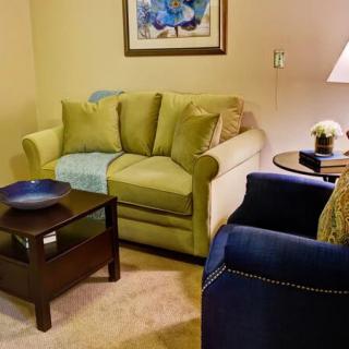 Cozy living room with a green sofa, blue armchair, and soft lighting.