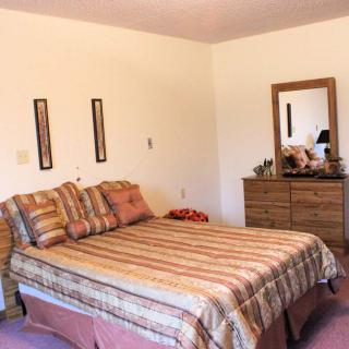 A cozy bedroom with a neatly made bed and a dresser topped with a mirror.