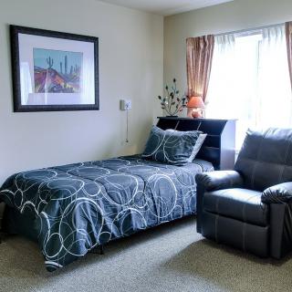 A cozy bedroom with a single bed, armchair, and colorful decor.
