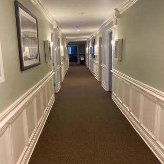 A well-lit interior hallway featuring doors on either side and a carpeted floor.