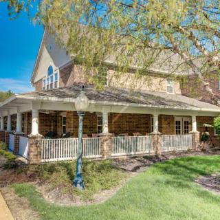 A spacious residential house with a wraparound porch and well-maintained landscaping.