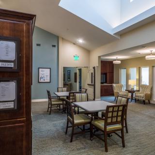 A modern and spacious room with tables and chairs arranged neatly, featuring ample lighting.
