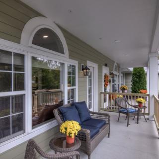 A cozy porch with outdoor seating and decorative flowers.