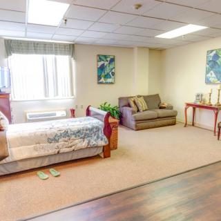 A spacious bedroom with a bed, couch, and table, featuring warm lighting and decor elements.