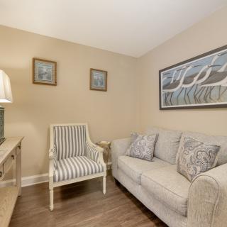 A cozy living room with a sofa, striped chair, and decorative wall art.