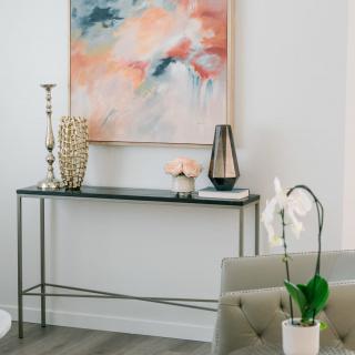 A modern interior with a minimalist console table, abstract artwork, and decorative vases.