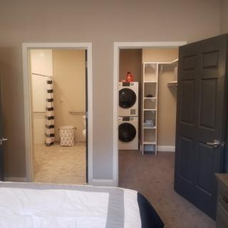 A bedroom view showing an adjacent bathroom and a connected laundry area with a walk-in closet.