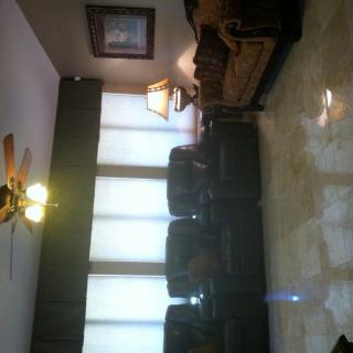 A cozy living room with sofas, a lamp, and ceiling fan.
