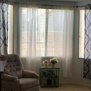 A cozy living room corner with natural light streaming through sheer curtains.