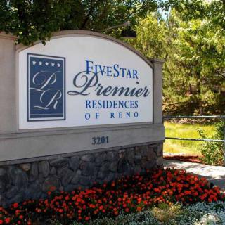 Entrance sign for Five Star Premier Residences of Reno, surrounded by flowers and trees.