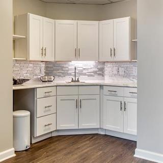 A modern corner kitchen with white cabinets and a stylish backsplash.