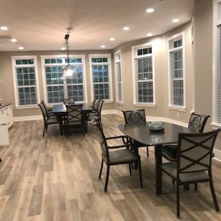 A modern dining area with wood flooring, ample windows, and stylish lighting.