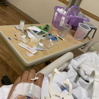 A patient in a hospital bed with medical supplies on a nearby table.