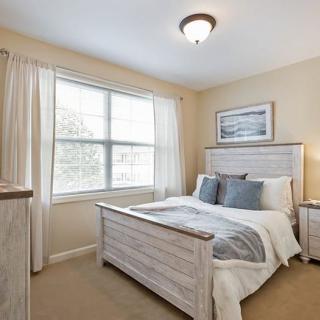 A cozy bedroom with elegant decor, featuring a bed, nightstands, and a large window.