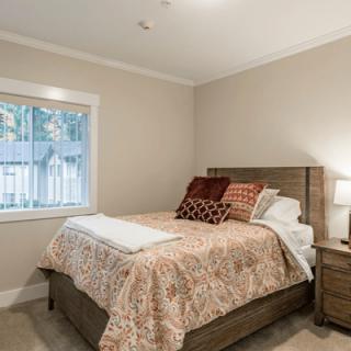 A cozy bedroom with a neatly made bed and wooden furniture.