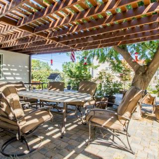 A cozy outdoor patio with chairs and a table under a pergola, providing a shaded area in the backyard.