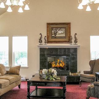 A cozy living room with a fireplace, elegant chandeliers, and comfortable seating.