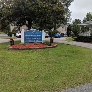Entrance sign of a residential area with landscaped lawn and trees.