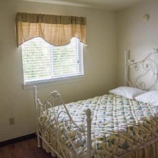 A small bedroom with a metal-framed bed and curtained window.