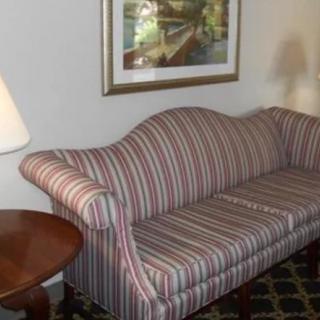 A striped sofa with a round table and lamp in a living room setting.