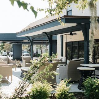 Outdoor patio seating area at a restaurant, featuring tables and chairs under a shaded pergola.