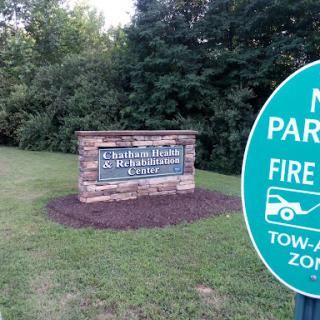 A park entrance sign with a warning about fire lanes and towing regulations.