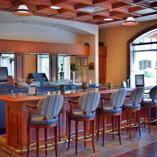 An empty and cozy bar with a wooden counter and high-backed chairs.