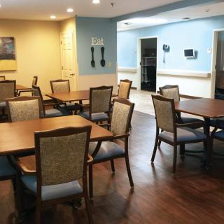 A cozy dining area with neatly arranged tables and chairs on a wooden floor.