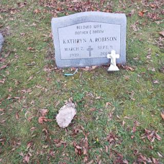 A serene grave marker surrounded by fallen leaves in a cemetery.