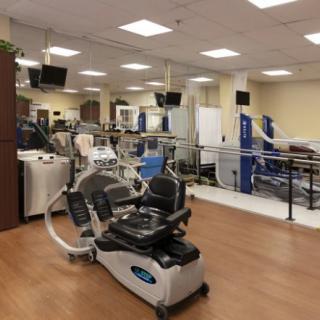 A fitness center with various exercise machines and equipment arranged neatly inside a well-lit room.