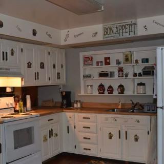 A cozy kitchen with white cabinets and various decorations.