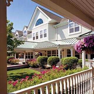 A picturesque view of a house with a well-maintained garden and blooming flowers, as seen from the porch.
