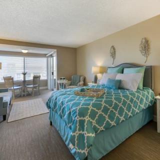 A modern and stylish bedroom with blue bedding and a well-furnished living area.