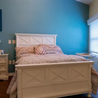 A cozy bedroom featuring a white bedframe against a vibrant blue wall.