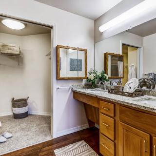 A contemporary bathroom with a wooden vanity, double sinks, and ample lighting.