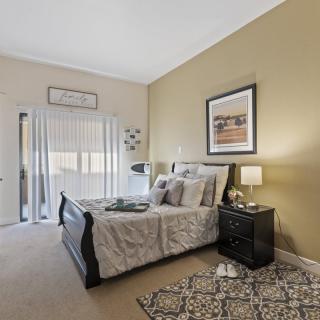 A cozy bedroom with a neatly made bed, nightstand, and lamp alongside decorative wall art.