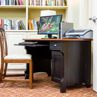 A home office setup featuring a desk with a computer, chair, and bookshelf.