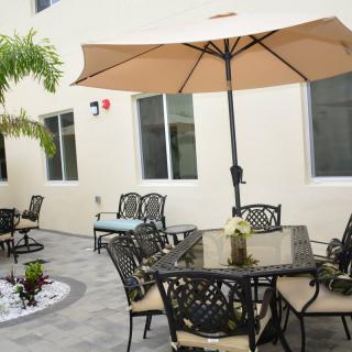 A cozy outdoor patio area with decorative furniture and a large umbrella.