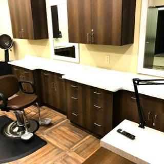 A modern barbershop setup featuring a stylish haircut station with cabinetry and a large mirror.