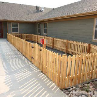 A residential house with a wooden fenced yard and adjacent sidewalk.
