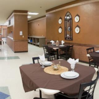 A neatly set dining area in a restaurant with tables and chairs, featuring elegant decorations on the walls.
