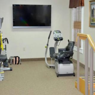 A rehabilitation room equipped with exercise machines and a television.