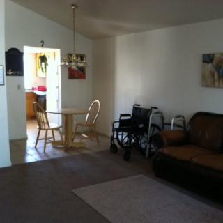 A cozy living room with a dining area and a wheelchair next to a sofa.