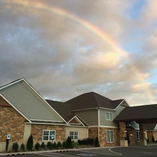 A beautiful rainbow arching over a charming building under a cloudy sky.