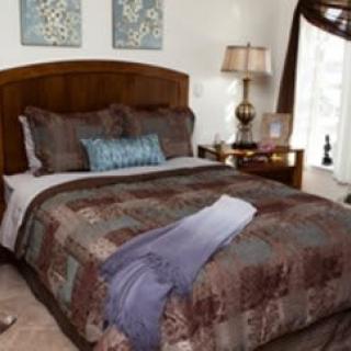A cozy bedroom with a well-decorated bed, soft pillows, and a bedside lamp.