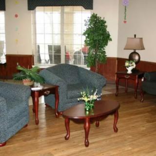 A cozy living room with comfortable sofas, wooden tables, and decorative plants.