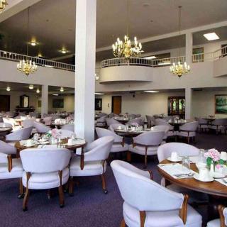 A spacious and elegant dining area with chandeliers and neatly arranged tables and chairs.