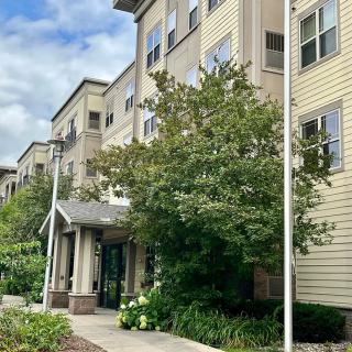 Exterior view of a residential apartment building with surrounding trees and entrance.