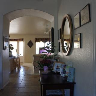 A cozy hallway with a decorative mirror and furniture, leading into a warmly lit living room.